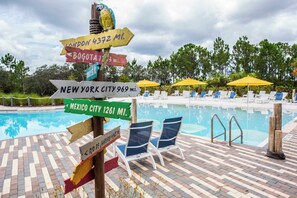 Dive into relaxation at our resort-style pool, complete with cheerful yellow umbrellas, comfy lounge chairs, and a playful global signpost pointing your next adventure!