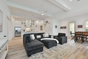 Overview of living area with sectional, kitchen table and kitchen area.
