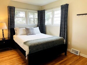 This bedroom with queen size bed also has a dresser and closet with hangers.