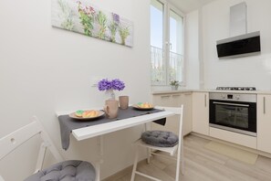 A well-lit dining area with a small table set for two, placed next to a fully equipped kitchen.