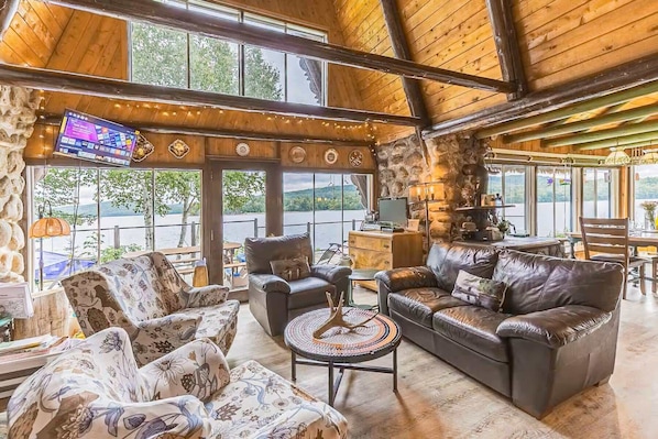 Spacious living room with stone fireplace and panoramic lake views