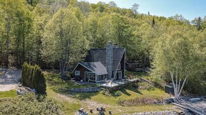Lakeside cabin surrounded by lush greenery and mature trees