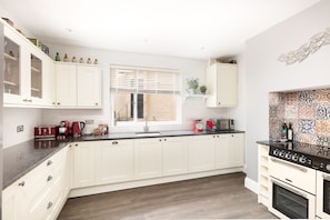 Spacious kitchen with double oven, dishwasher, washing machine and all utensils, plates, glasses to prepare a fine feast.