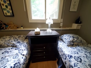Second bedroom with two twin beds, sheets and pillows.