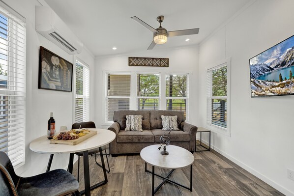 The snug living room seamlessly transitions into a quaint dining area, creating an intimate and charming space .