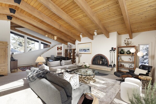 Second family room on the 3rd level with wood-burning fireplace, piano, and expansive views of the gardens