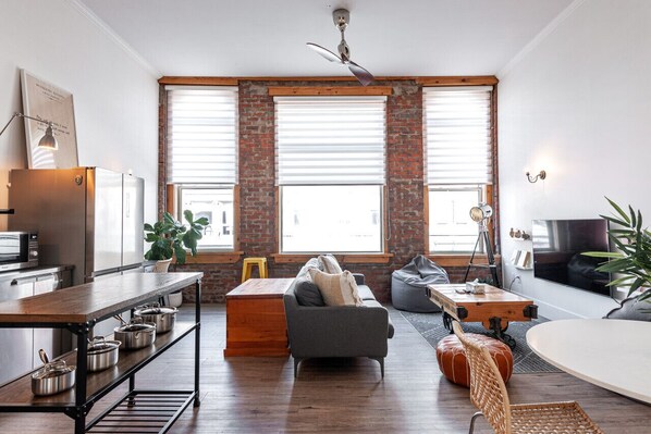 Step into The Chelsea Loft's living area, where London's Kings Road meets Stratford’s charm. High ceilings and immense windows create an airy, light-filled space, perfect for relaxation after exploring nearby Stratford Festival theatres and Avon River.