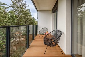 Private balcony with a small table and chairs, overlooking a green space.