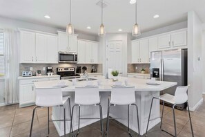 Modern kitchen of the home in Kissimmee Florida - Countertop table with high chairs - Where you can quickly grab a snack or drink your coffee and tea - Contemporary design with clean lines and minimalist aesthetics - Stainless steel appliances