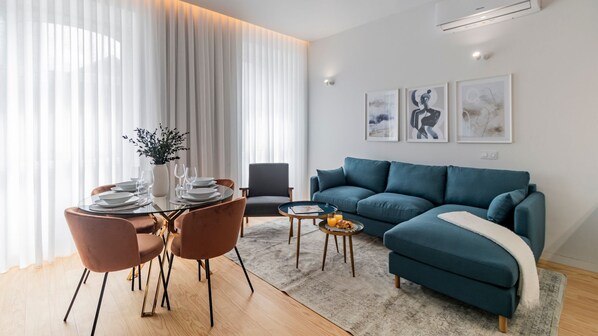 Spacious living area with a large, comfortable sofa, a round dining table, TV, and seamless connection to the kitchenette, bathed in ample natural light for a bright and inviting atmosphere.
#comfort