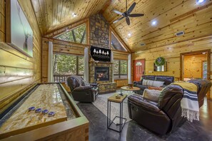 Living room is full of cozy seating, Smart TV, and shuffle board.