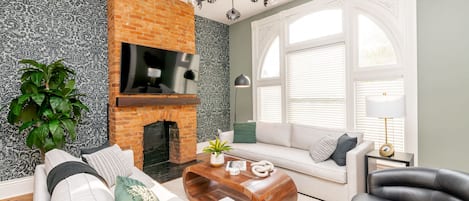 Stylish living room with exposed brick decorative fireplace and 4K TV