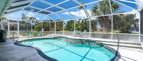 Screened in kidney shape pool with an elevated deck and a handrail entry.