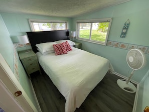 Full bed with nightstands and floor fans.
