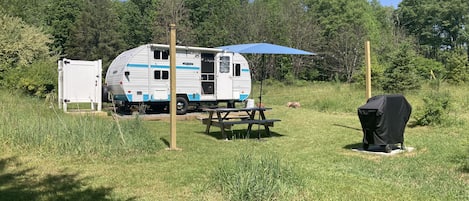 Camper with picnic table, umbrella and gas grill.