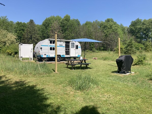 Camper with picnic table, umbrella and gas grill.