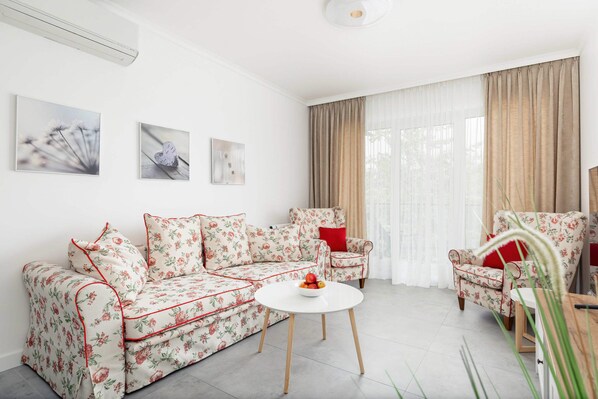 Bright and cozy living room with a sofa bed, TV and access to balcony.