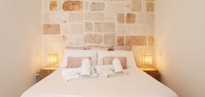 master bedroom with king-size bed and caratheristic stone wall