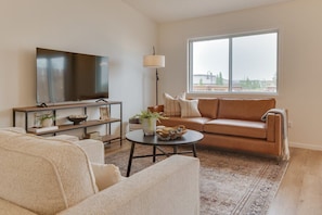 Unwind in our inviting living room, featuring a luxurious leather couch, two oversized accent chairs, a 58-inch Smart Roku TV for entertainment, all nested on a plush rug for ultimate comfort.