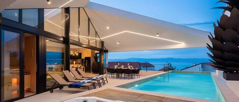 Geräumige Terrasse der modernen kroatischen Villa Sandorin Sutivan mit privatem Pool, Whirlpool, Sonnenliegen und Esstisch im Freien mit Stühlen und Blick auf das Meer und die Inseln