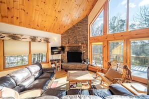 Living room features large cathedral ceiling with a wall of windows