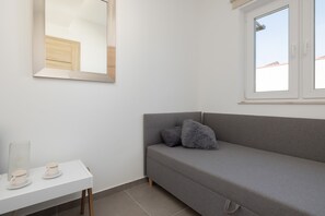 A bright single bedroom with a minimalist design and plenty of natural light coming through the window.