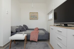 A corner of the living room, featuring a comfortable seating arrangement and a cabinet with a TV.