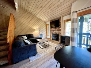 Living room with large flatscreen TV and pellet stove.