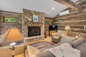 The cozy living room offers plenty of comfortable seating and a wood burning fireplace