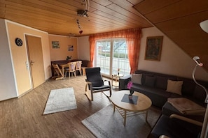 Großes Wohnzimmer mit gemütlicher Essecke und Balkon