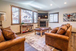 Living space with comfortable seating, fireplace, and large TV.