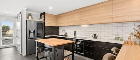 Kitchen with island bench and built in desk which is perfect for working or meals