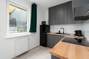 A modern kitchen with sleek dark cabinetry, wooden countertops, and fully equipped with appliances.
