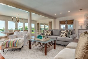 Relax in this beautifully designed living room featuring soaring ceilings, ample seating, and elegant coastal decor. Perfect for family gatherings on Dauphin Island.