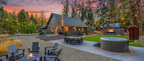 Relax and be allured with this outdoor space adorned with market lights, a generous patio table, turf grass, putting green, and a soothing hot tub."