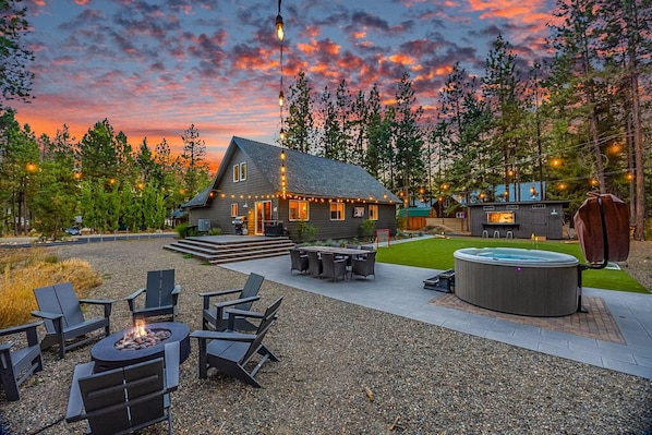 Relax and be allured with this outdoor space adorned with market lights, a generous patio table, turf grass, putting green, and a soothing hot tub."