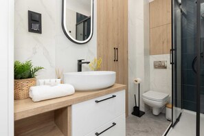 A contemporary bathroom with a walk-in shower, a wooden vanity, and stylish black fixtures.
