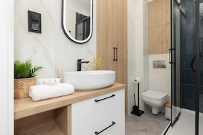A contemporary bathroom with a walk-in shower, a wooden vanity, and stylish black fixtures.