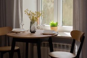 A close-up of a dining table set for two, with elegant dinnerware and a vase of fresh flowers.