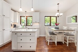 Welcome to our white-themed kitchen and dining table, a versatile space that caters to both small and large families. It's a stylish and inviting hub for shared meals and cherished moments.