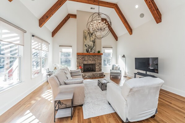 Conversational den, 55-in TV,  fireplace chandelier, pool view and wooded view.