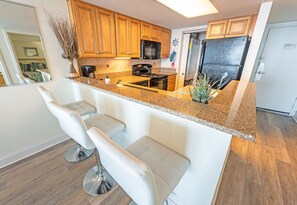 - Stylish kitchen features a sleek granite breakfast bar with modern seating, perfect for morning coffee or casual meals - Open-concept design keeps you connected to the living space while cooking - Welcoming spot to dine, or simply enjoy a conversation