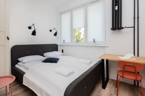 A cozy bedroom featuring a comfortable bed, simple decor, and a small desk by the window.
