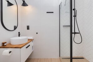 A stylish bathroom with a walk-in shower, minimalist black fixtures, and a clean design.
