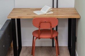 A small workspace setup with a wooden table and a red chair, ideal for working or studying.
