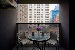 Balcony view with a small round table, chairs, and a backdrop of modern buildings.