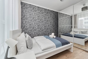 Cozy bedroom with a double bed, blue bedding, and a decorative gray accent wall.