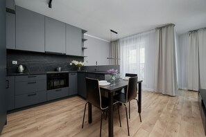 Modern kitchen with dark gray cabinets, a dining table, and large windows.