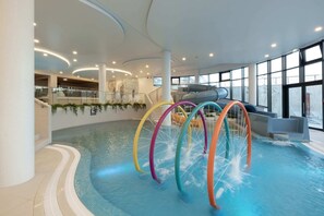 An inviting indoor pool equipped with colorful water attractions and large windows, perfect for family fun.

