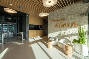 A welcoming lobby area with wooden accents, warm lighting, and an “Aqua” sign on the wall.

